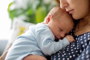 Young mother, holding tenderly her newborn baby boy